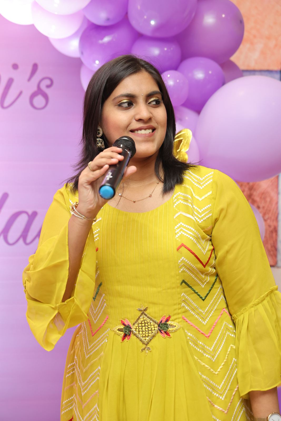 Anchor Ananya Kundu smiling with a microphone, warm close-up