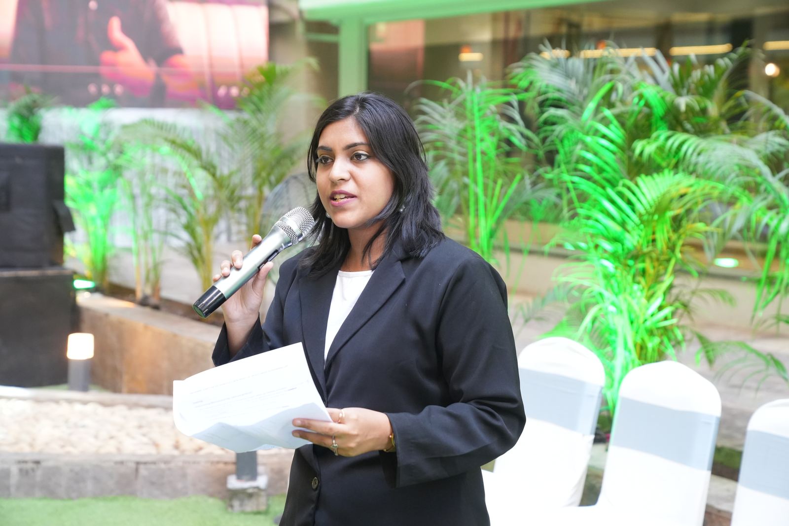 Anchor Ananya Kundu presenting at an outdoor corporate evening