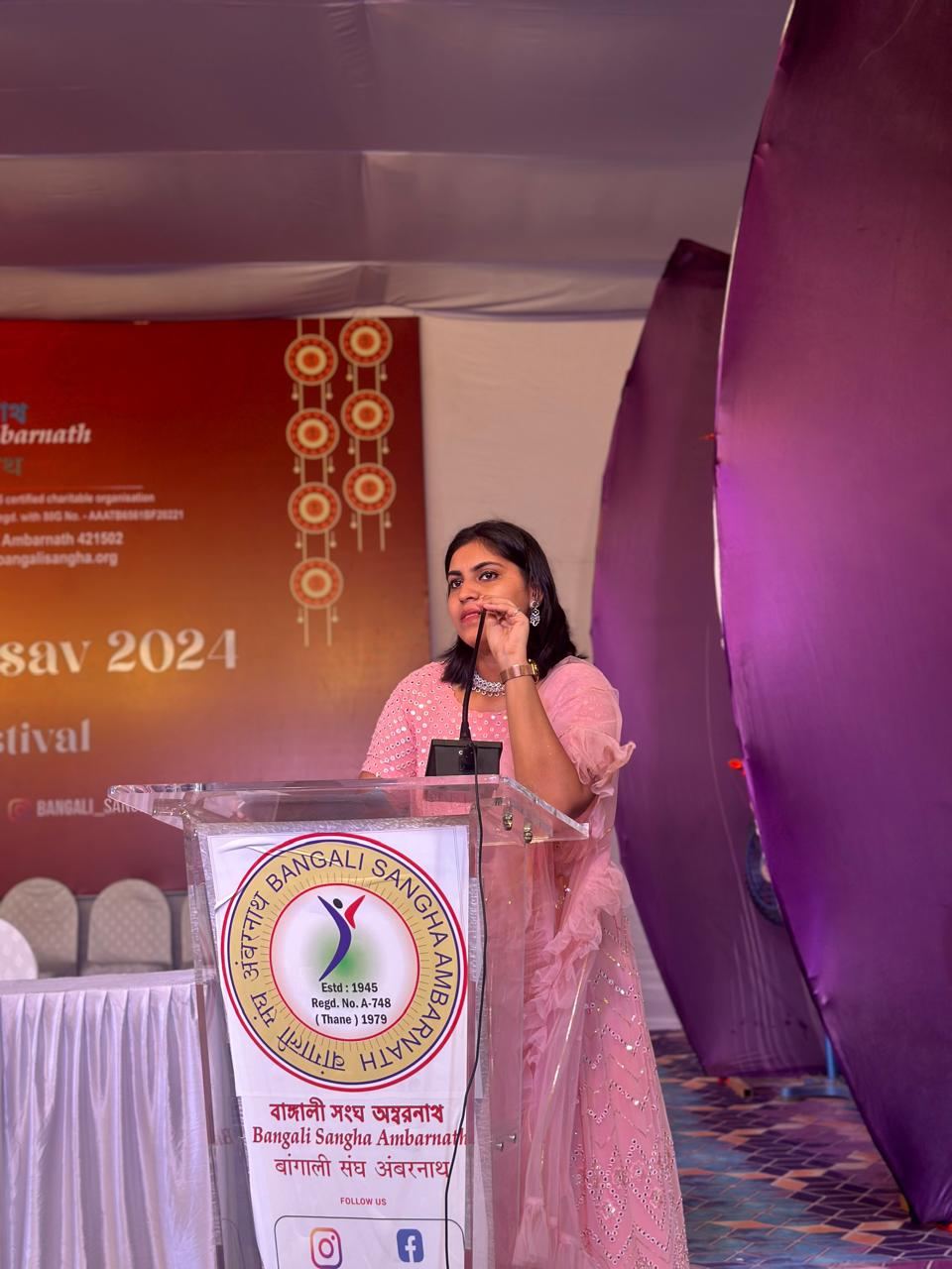 Anchor Ananya Kundu at a community festival podium